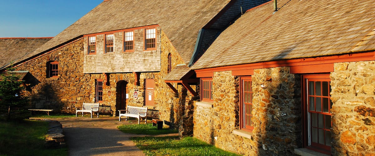 A stone building with a sloped roof and red window frames.