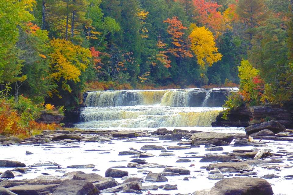 A waterfall surrounded by autumn-colored trees.