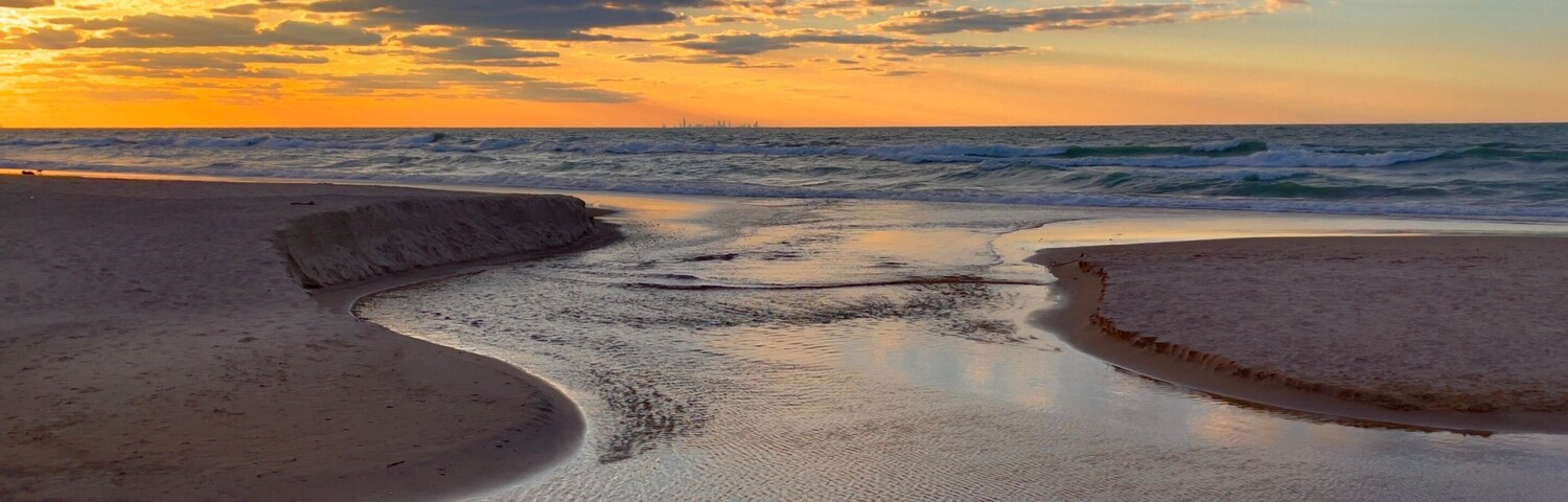 Una playa con ondulaciones en la arena y un cielo al atardecer.