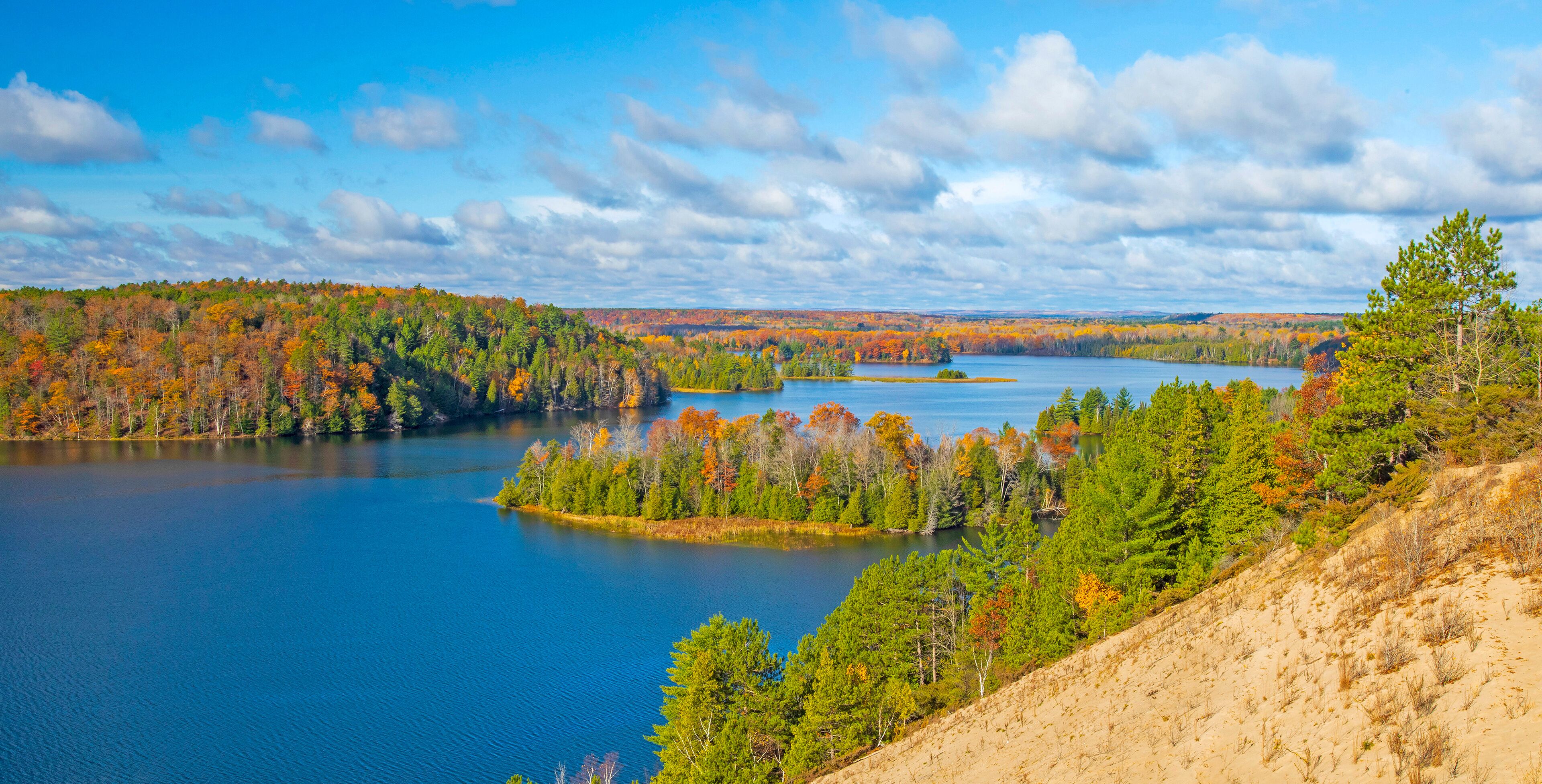 A lake surrounded by autumn-colored trees and a clear sky.