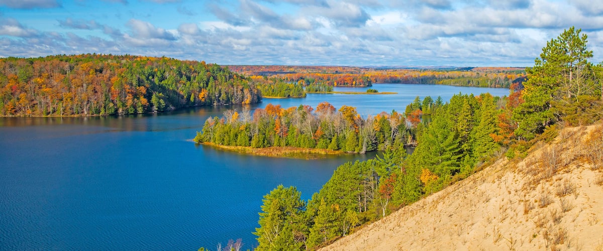 A lake surrounded by autumn-colored trees and a clear sky.