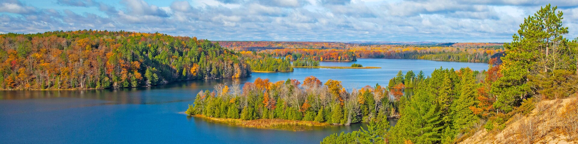 A lake surrounded by autumn-colored trees and a clear sky.