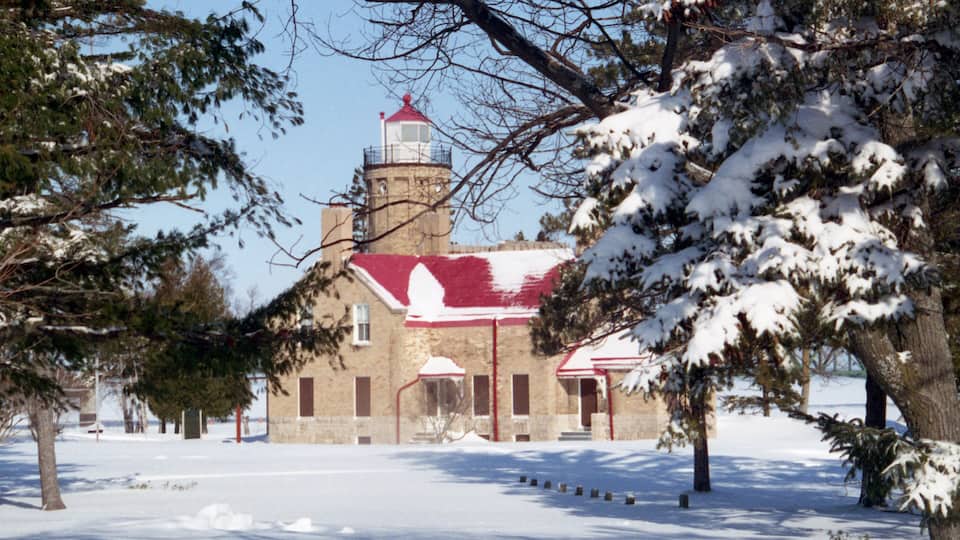 A snow-covered building with a red roof and a tower.