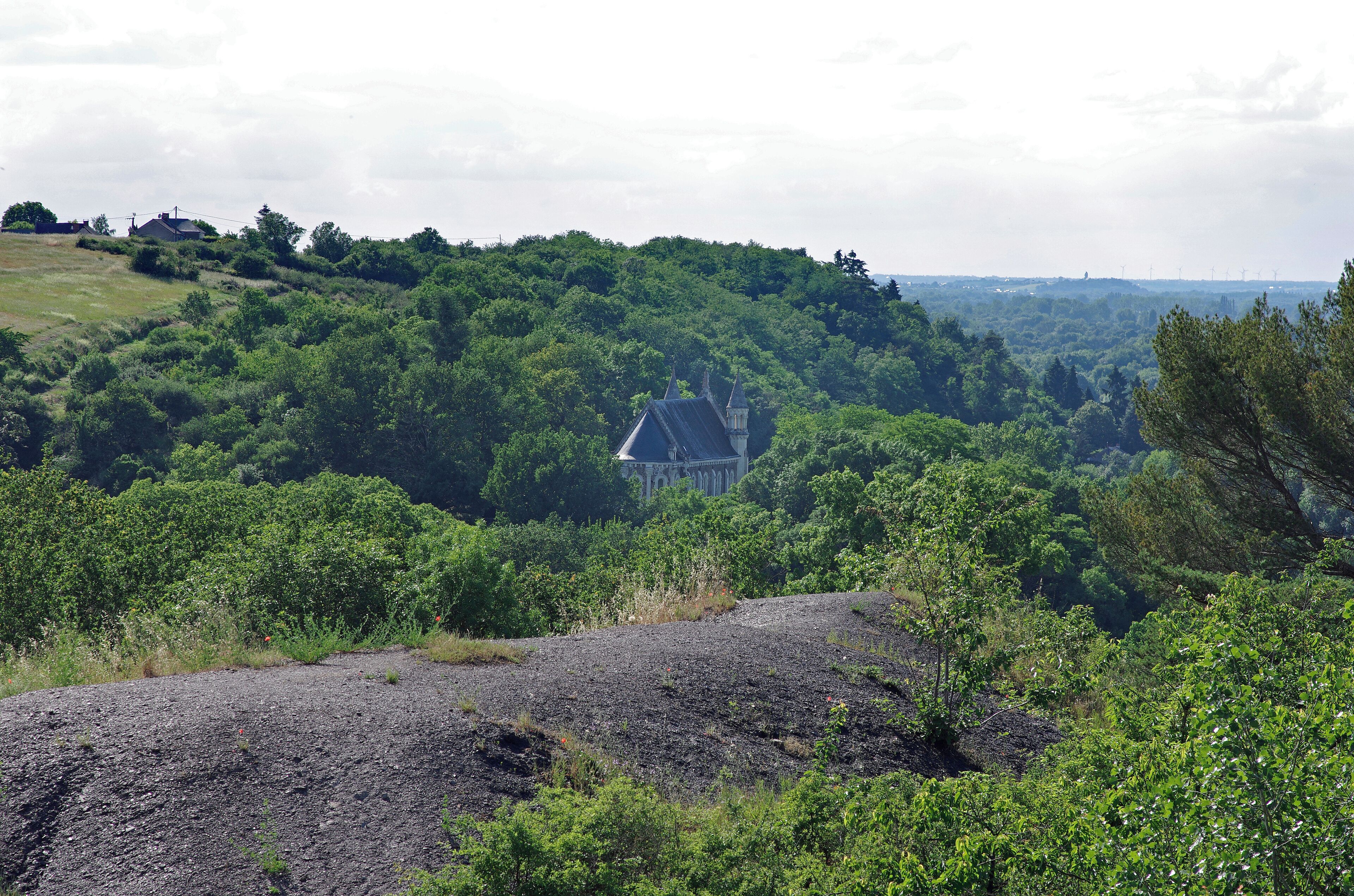 Chaudefonds-sur-Layon (Maine-et-Loire) Mine de charbon des Malécots. Le crassier et la chapelle Sainte-Barbe, chapelle des mineurs. Cette mine de charbon a fermé en 1964. Ce fut la dernière mine en activité du bassin houiller de la Basse Loire, sillon houiller fusiforme allant de Nort-sur-Erdre en Loire-Atlantique à Doué-la-Fontaine en Maine-et-Loire. Le charbon de terre était déjà exploité, de manière artisanale, au XVe siècle. L'exploitation industrielle se développe au XIXe siècle, et le puits N°1 atteint une profondeur de 360 mètres. La production atteindra son apogée au milieu du XIXe siècle, mais la rentabilité reste faible : environ 150 à 200 kg de houille par homme et par jour. Dans l'ensemble, l'exploitation du bassin de Basse-Loire fut décevante: le tonnage extrait est de l'ordre de 5 millions de tonnes, à comparer avec les 2,5 milliards de tonnes de houille extraites dans le bassin du Nord Pas-de-Calais. Le puits N°1 connu un violent coup de grisou en 1869 qui fit 5 morts. <a href="http://www.stebarbe.com/malecots.htm" rel="nofollow">www.stebarbe.com/malecots.htm</a> <a href="https://fr.wikipedia.org/wiki/Site_des_Malécots" rel="nofollow">fr.wikipedia.org/wiki/Site_des_Malécots</a>