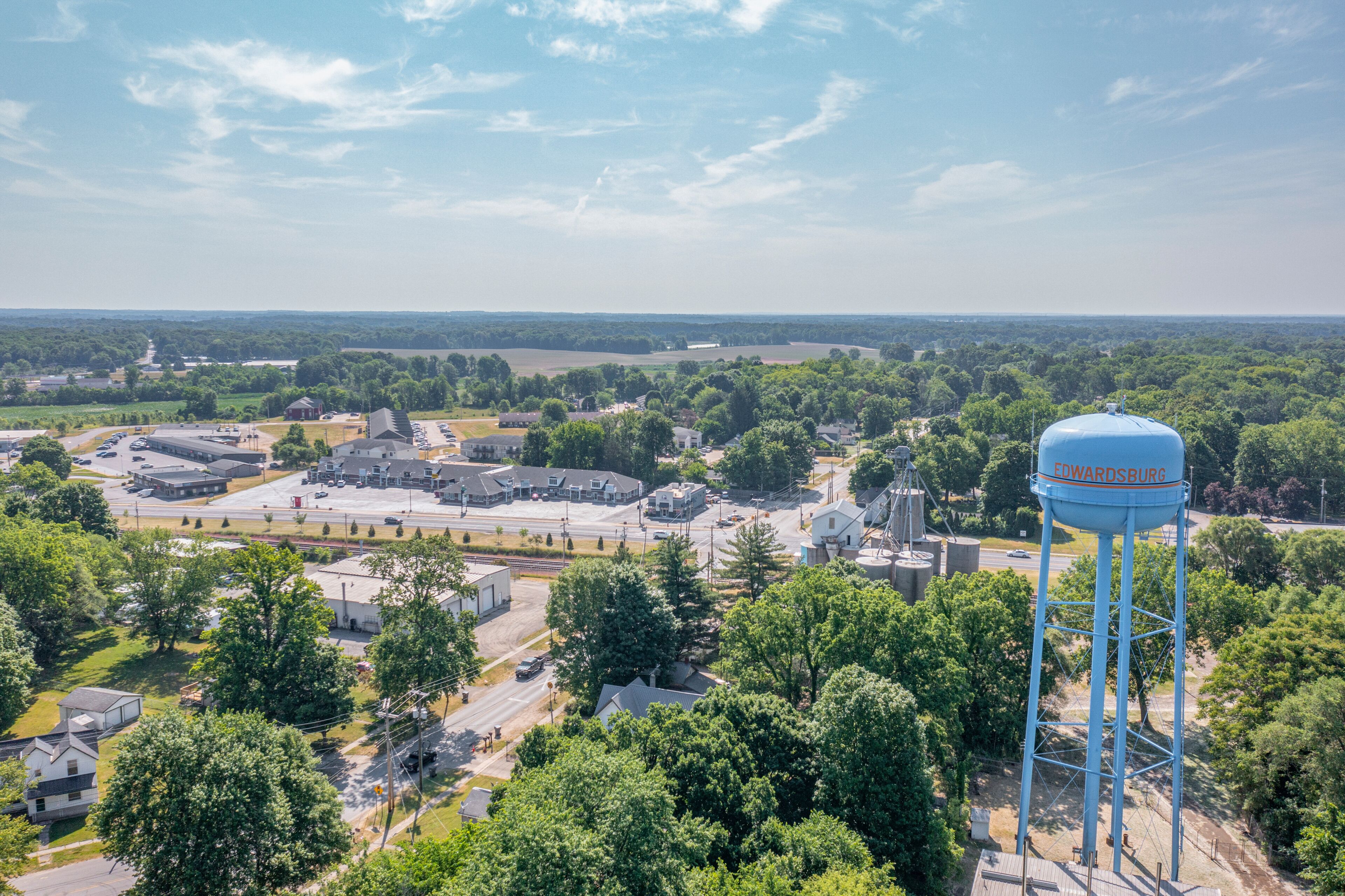 A water tower labeled 'EDWARDSBURG' amidst a town with buildings, roads, and surrounding greenery.