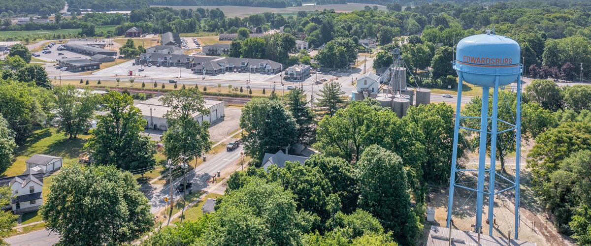 A water tower labeled 'EDWARDSBURG' amidst a town with buildings, roads, and surrounding greenery.