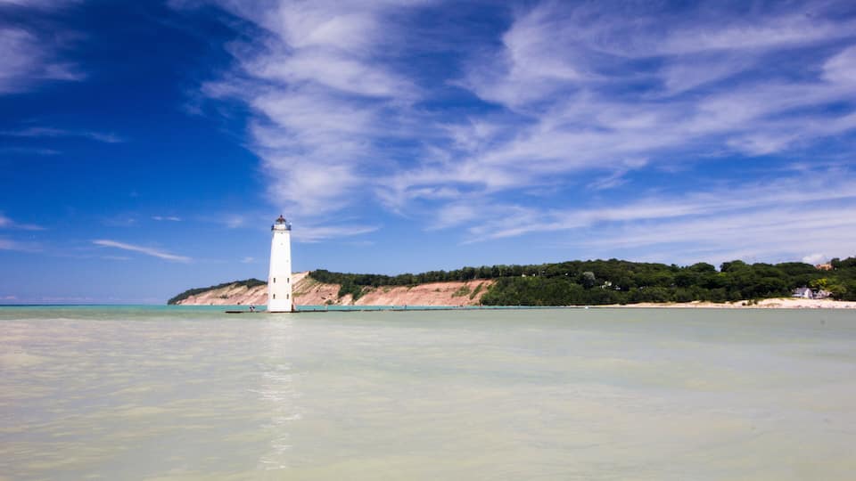 A lighthouse on a rocky coastline with clear blue skies.