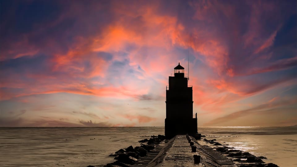 A lighthouse at sunset with a dramatic sky.