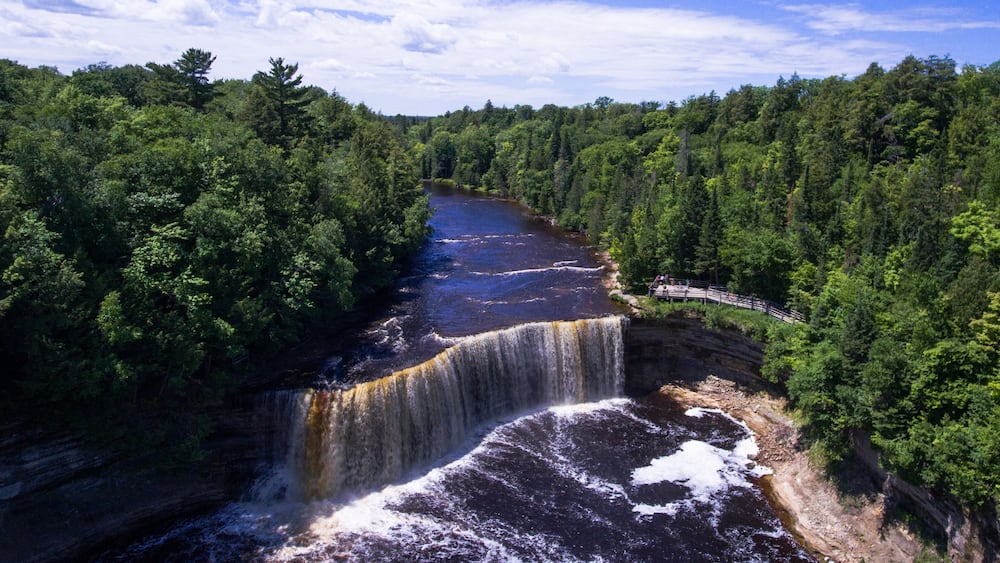 Une cascade se jetant dans une rivière, le tout étant entouré d’une forêt dense.