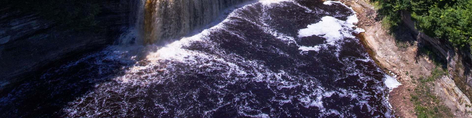 A waterfall cascading into a river surrounded by dense forest.