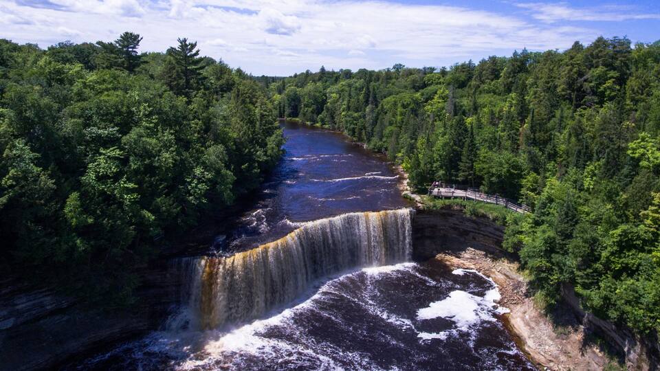 A waterfall cascading into a river surrounded by dense forest.
