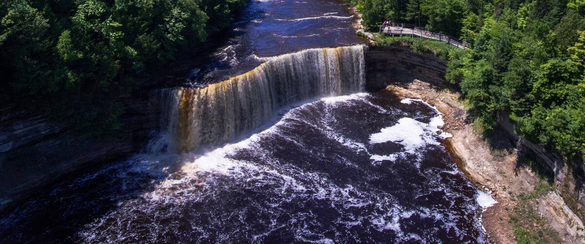 A waterfall cascading into a river surrounded by dense forest.