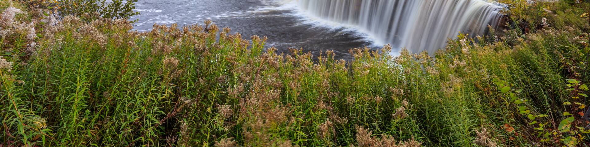 A waterfall in a forested area with autumn foliage.