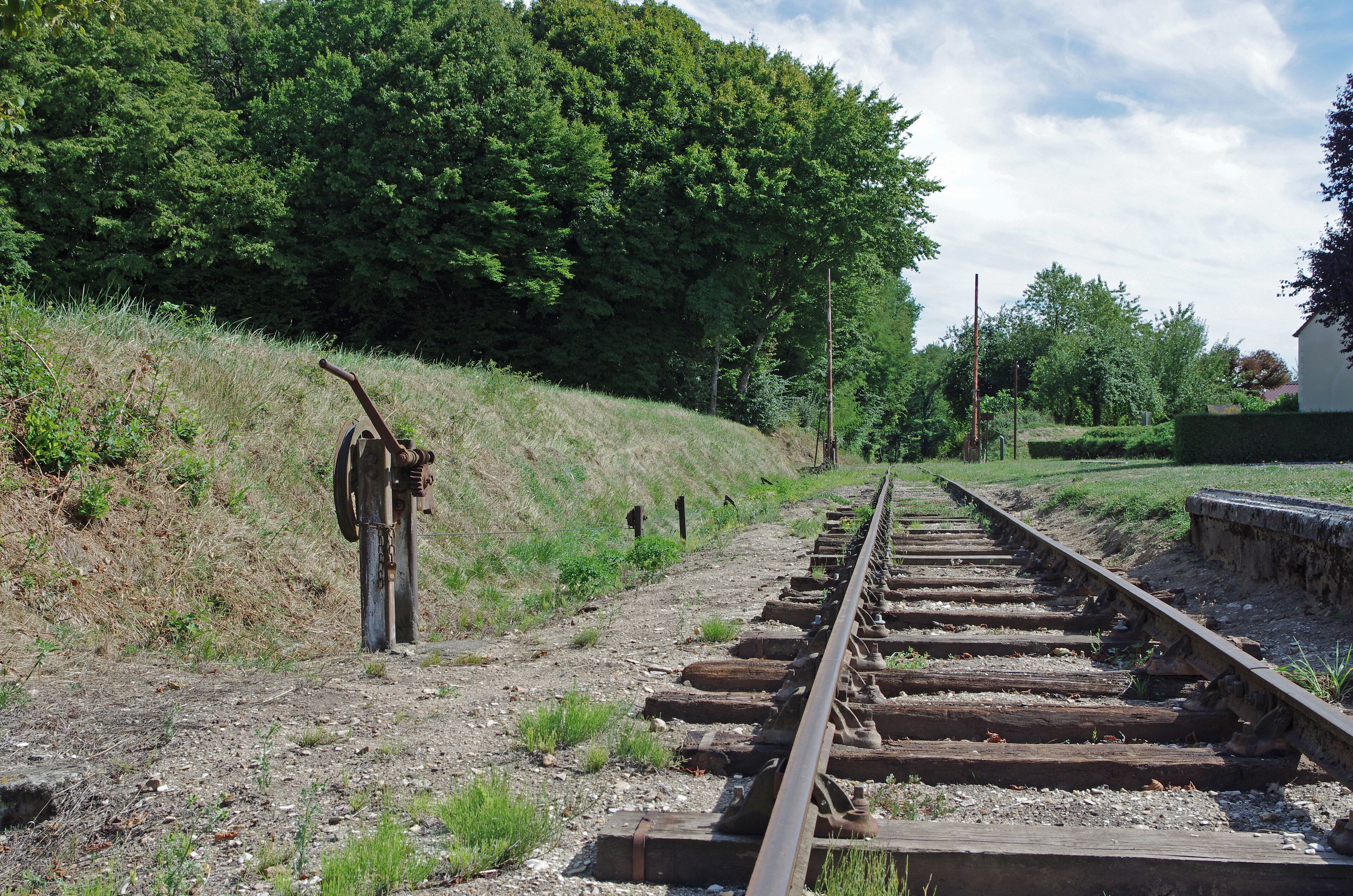 Heugnes (Indre) La gare. La voie métrique et le treuil de commande du passage à niveau. La gare d'Heugnes est une gare de la ligne de Salbris au Blanc. Elle est mise en service, le 17 novembre 1902. Le trafic voyageurs a cessé en 1980 et le trafic marchandises en 1988. La ligne a été inscrite au titre des monuments historiques en 1993. Pour la gare, sont conservés : le bâtiment voyageurs avec la halle marchandise accolée, le quai, la lampisterie-toilettes, le puits, le passage à niveau.