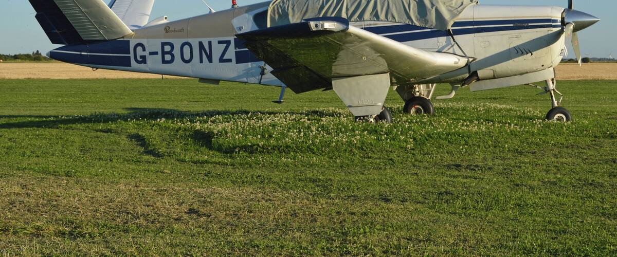A small propeller plane with the registration G-BONZ parked on a grassy field.
