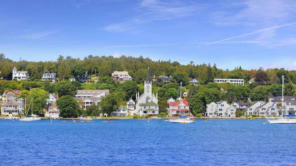 A coastal town with houses, a church, and boats on the water.