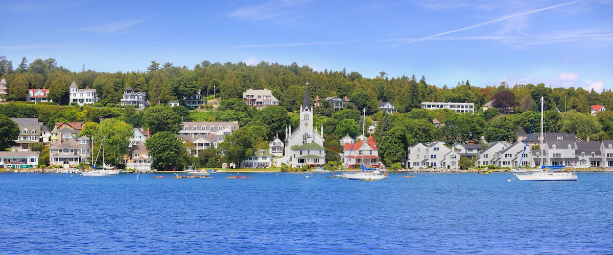 A coastal town with houses, a church, and boats on the water.