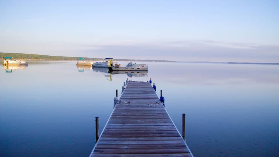 A wooden pier extending into calm water with boats docked at the end.