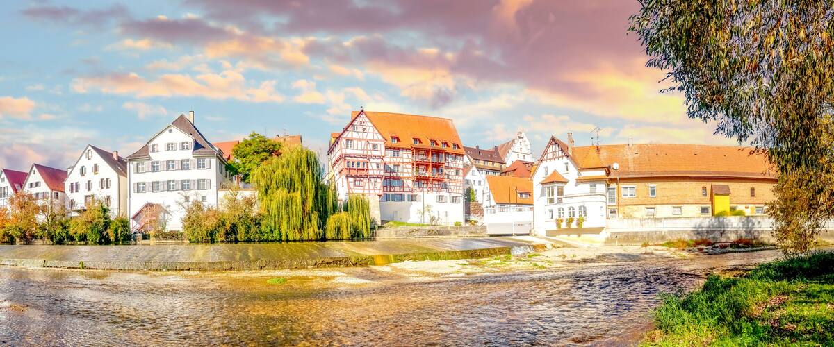 A riverside town with traditional half-timbered houses and a bridge.