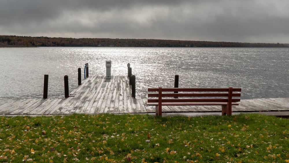 Une jetée en bois s’avançant dans un lac, avec un banc à son extrémité.