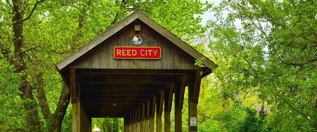 Covered wooden foot bridge over small peaceful creek in Reed City, Michigan.