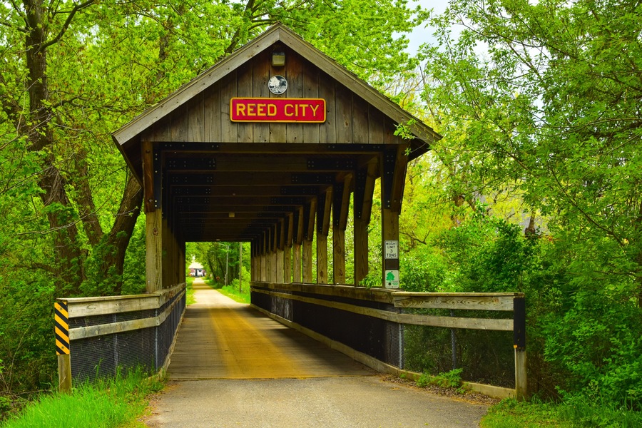 Covered wooden foot bridge over small peaceful creek in Reed City, Michigan.
