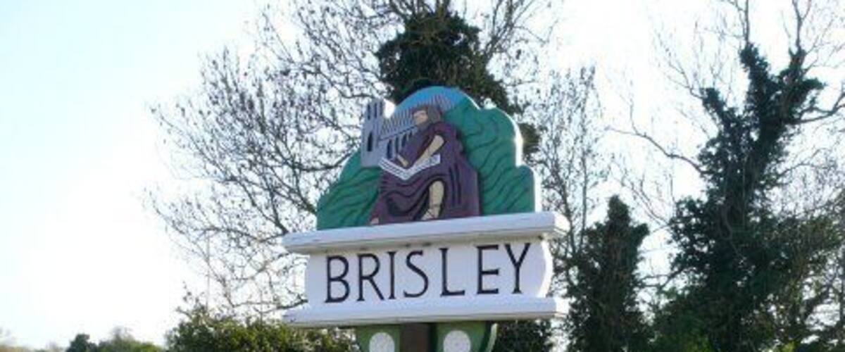 A signpost with the name 'BRISLEY' and a decorative emblem.