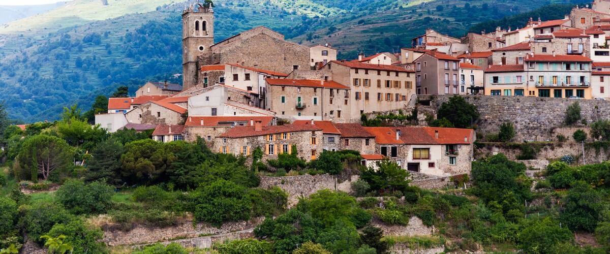 A hillside village with historic stone buildings and a church tower.
