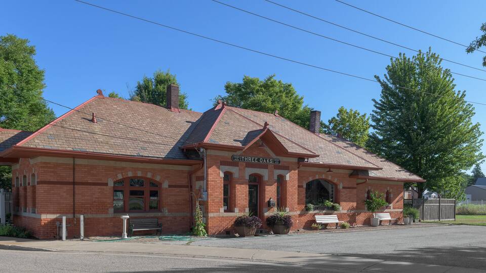 A brick building with a red roof, named "Three Oaks."