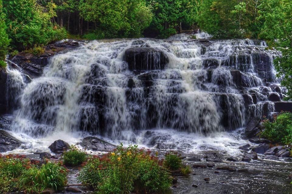A multi-tiered waterfall surrounded by lush greenery.