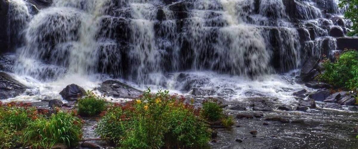 A multi-tiered waterfall surrounded by lush greenery.