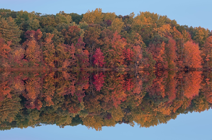 Autumn landscape of the shoreline of Long Lake with mirrored reflections in calm water, Yankee Springs State Park, Michigan, USA