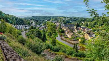 Une ville riveraine dotée de bâtiments historiques, d’un mur de pierre et d’une végétation luxuriante.