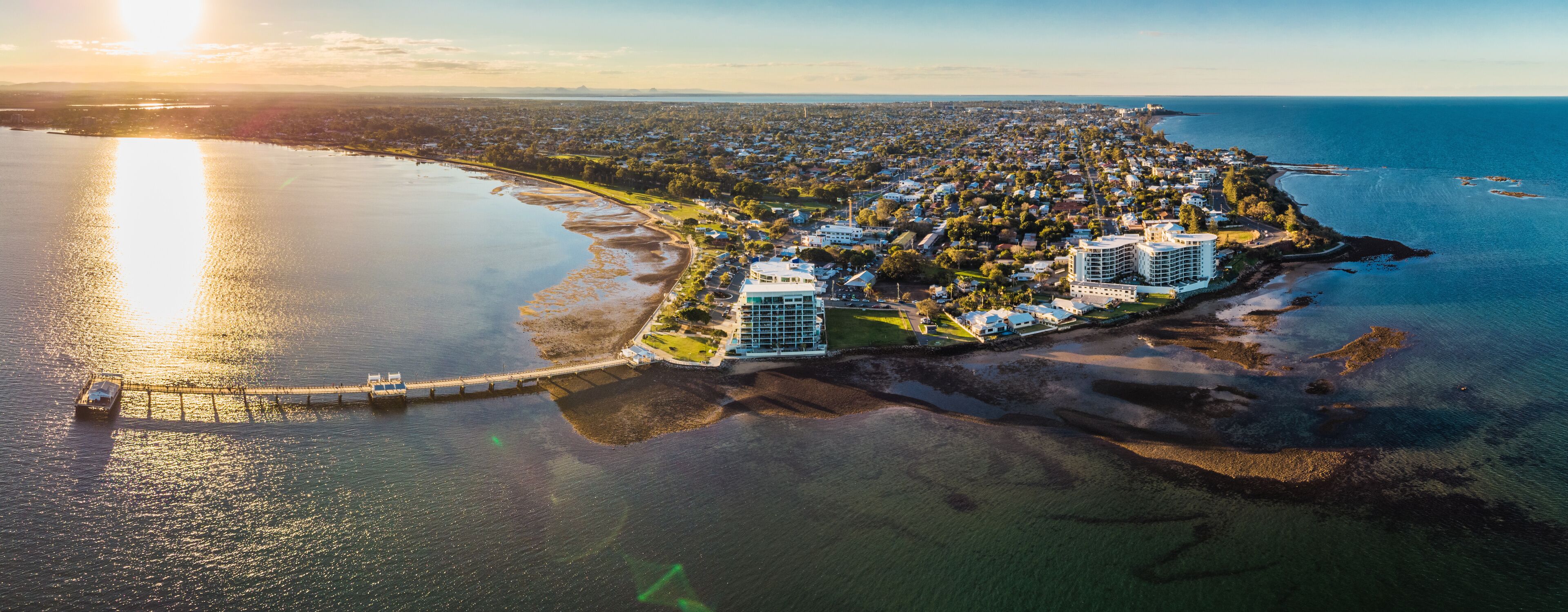 An aerial view of a coastal town with a marina, residential area, and a large hotel.