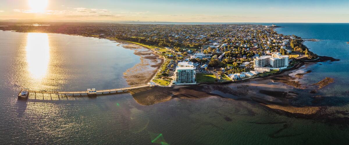 An aerial view of a coastal town with a marina, residential area, and a large hotel.
