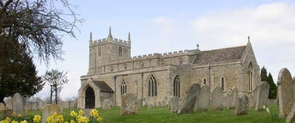 A historic church with a tall tower, surrounded by a cemetery with headstones.