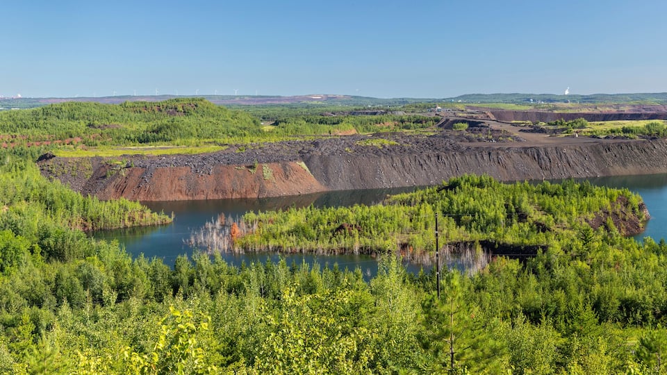 A landscape with a large body of water surrounded by green vegetation and mining areas.