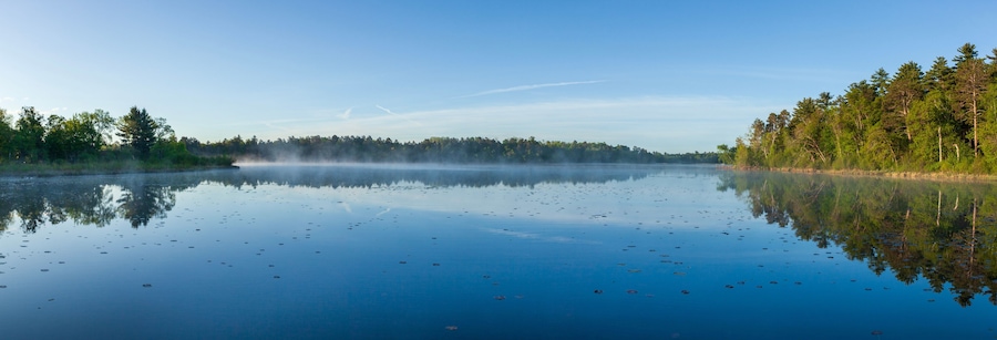 Panorama of a calm lake at dawn with pines on the shore in northern Minnesota