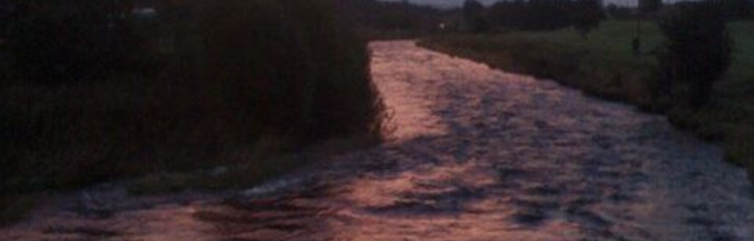 Un río que atraviesa un paisaje rural durante la puesta de sol.