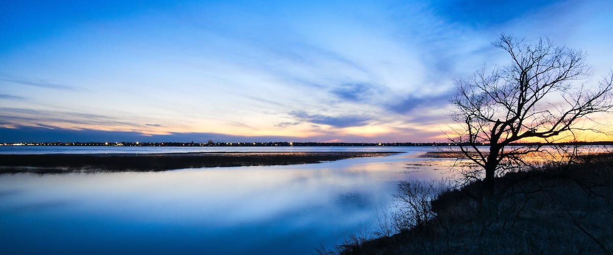 Bemidji, Minnesota, the 2018 Best Town in Minnesota is seen across Lake Bemidji where the Mississippi River flows toward the camera at sunset on a beautiful evening.