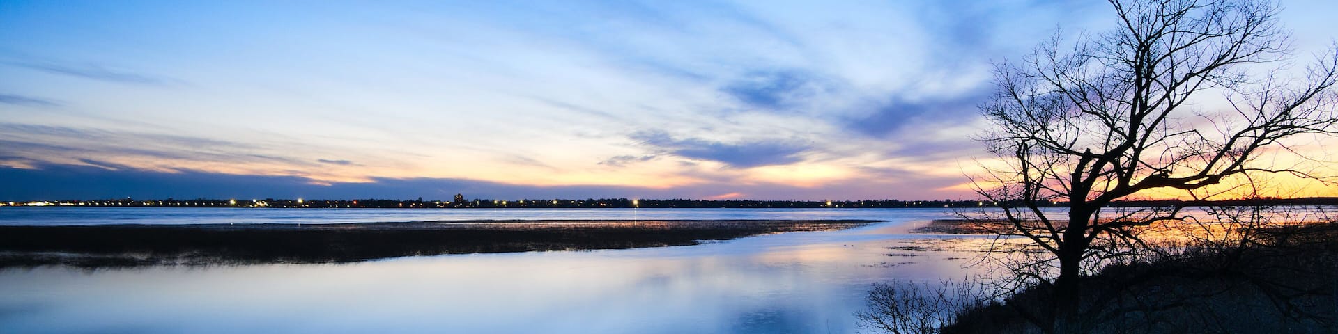 Bemidji, Minnesota, the 2018 Best Town in Minnesota is seen across Lake Bemidji where the Mississippi River flows toward the camera at sunset on a beautiful evening.