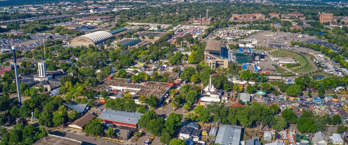 An aerial view of a city with a large stadium, various buildings, and a distant skyline.