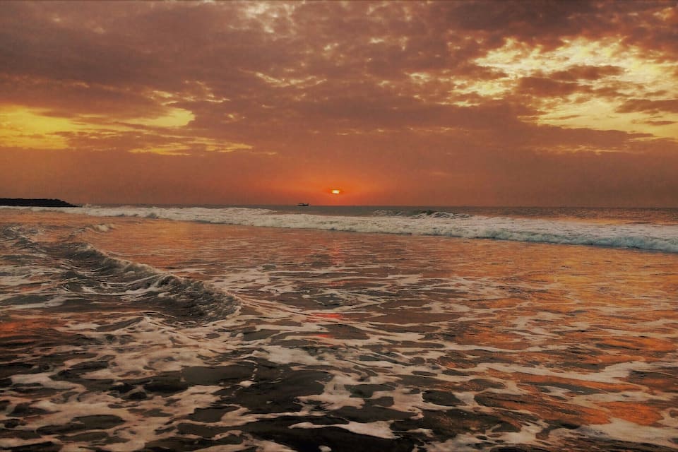 Una playa con olas y un atardecer.