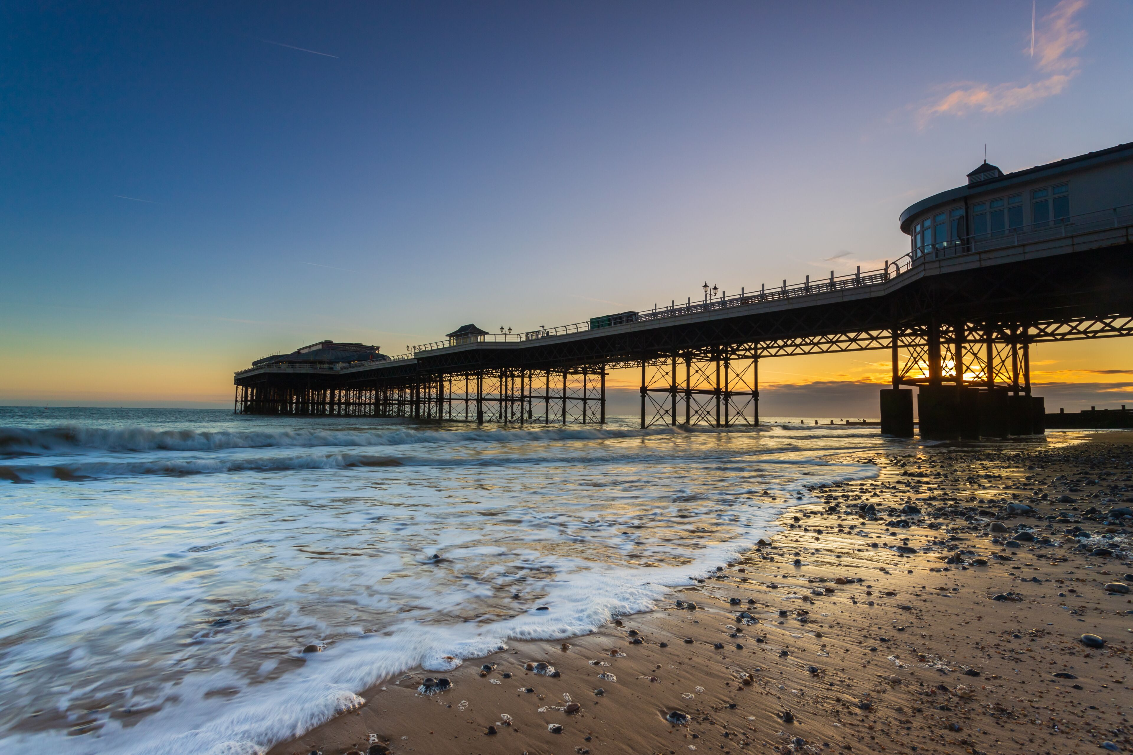 A pier extending into the ocean with waves crashing onto the shore.