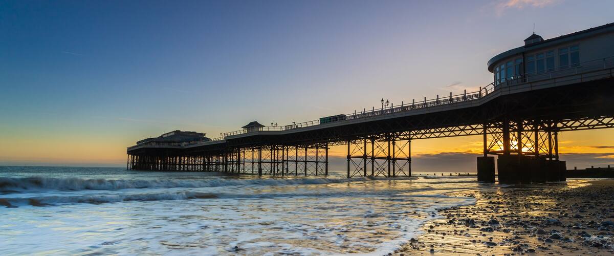 A pier extending into the ocean with waves crashing onto the shore.