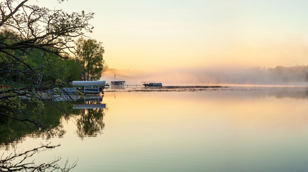 Panorama of a calm northern Minnesota lake and fog at dawn during spring with docks along the shoreline