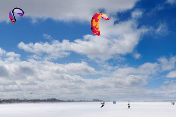 A snowy landscape with two kites flying in the sky.