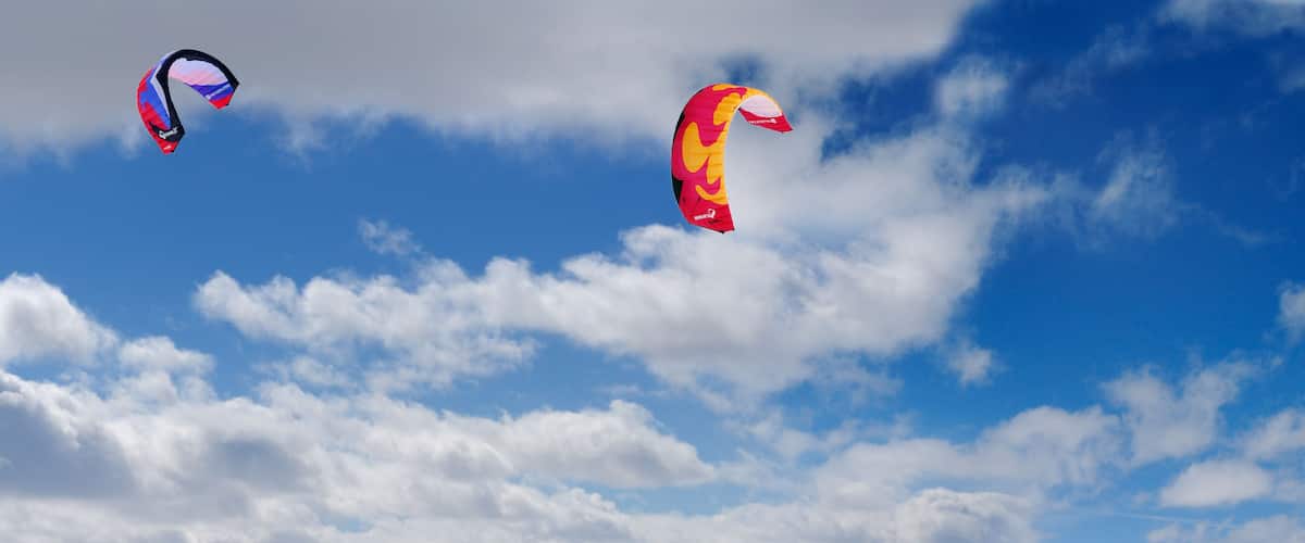 A snowy landscape with two kites flying in the sky.