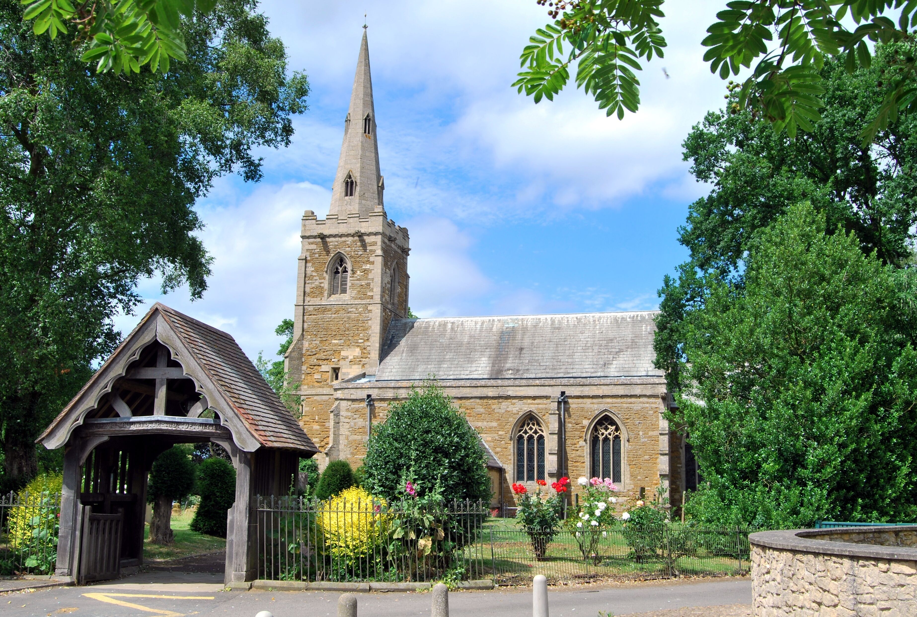 A church with a tall spire and a wooden entrance shelter.