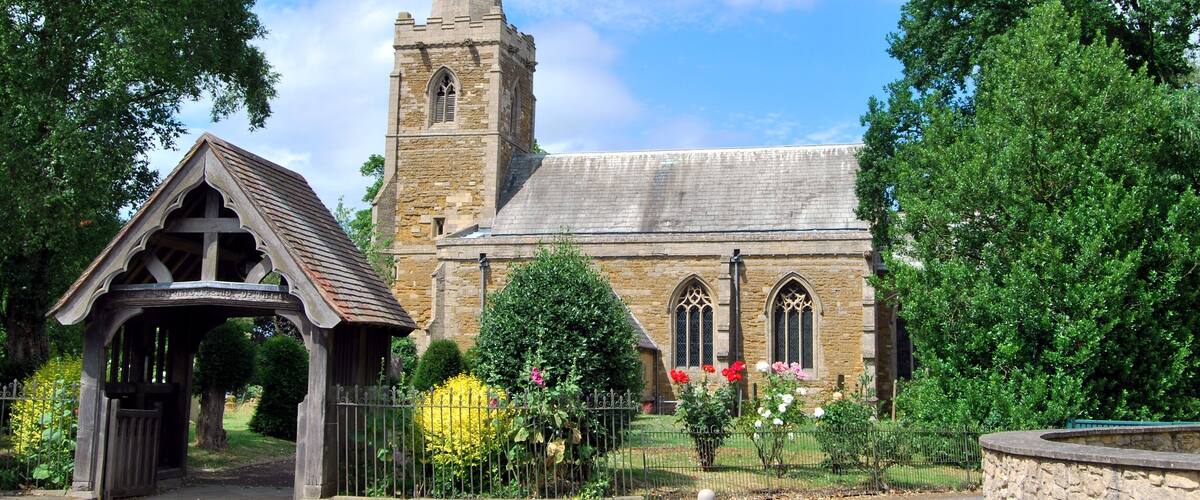 A church with a tall spire and a wooden entrance shelter.